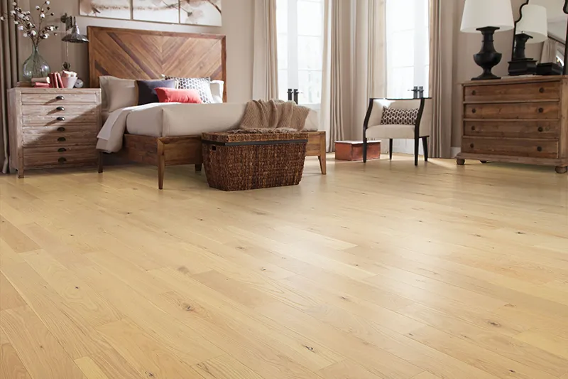 Brightly lit bedroom featuring newly installed, light-colored natural hardwood flooring with rustic wooden furniture.