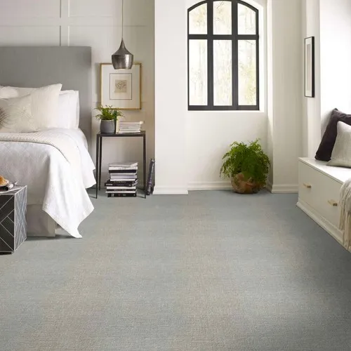 Light gray textured carpet tiles in a modern, brightly lit bedroom setting.